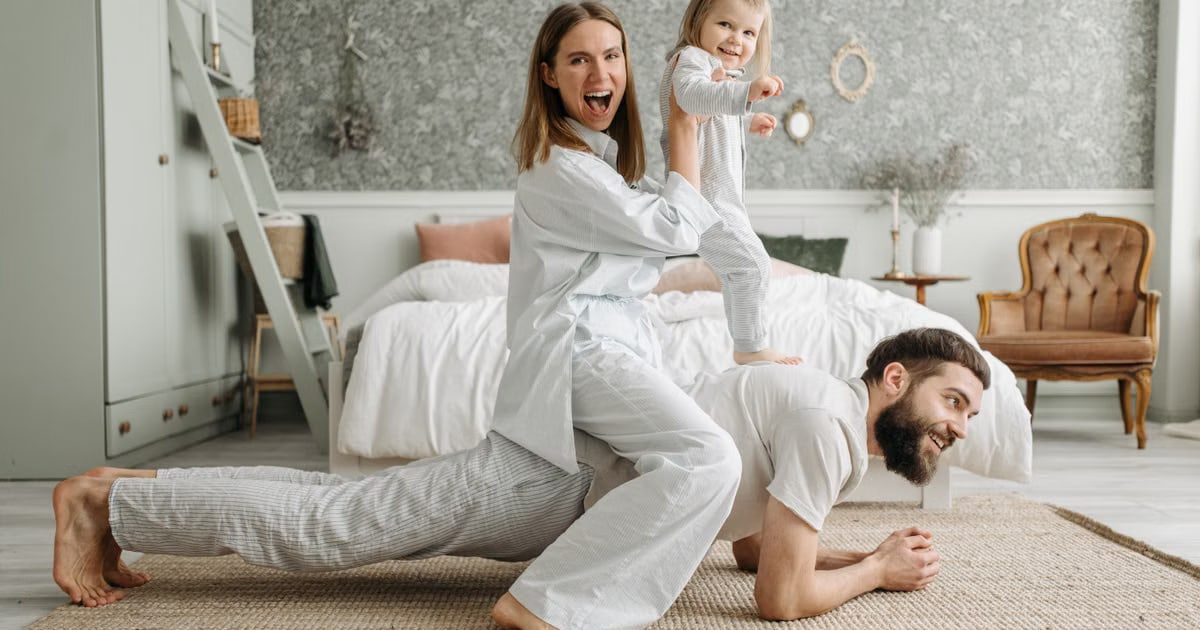 A cheerful family enjoys bonding and playing together on a cozy morning in a stylish bedroom.