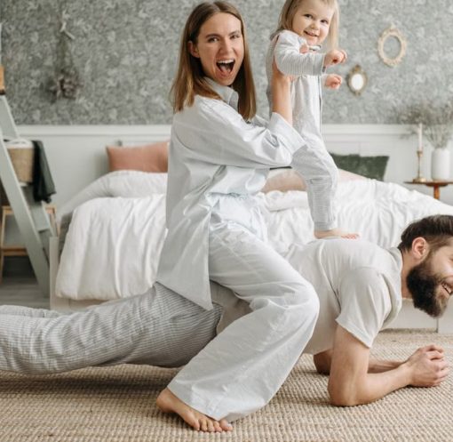 A cheerful family enjoys bonding and playing together on a cozy morning in a stylish bedroom.