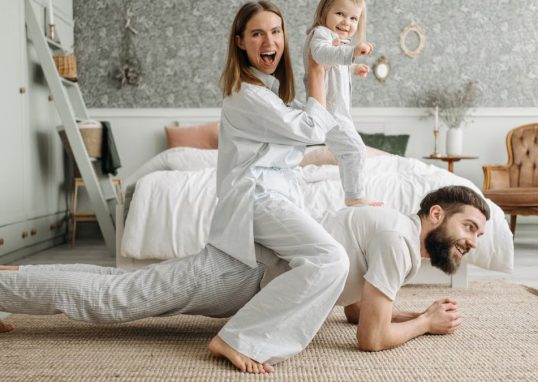 A cheerful family enjoys bonding and playing together on a cozy morning in a stylish bedroom.