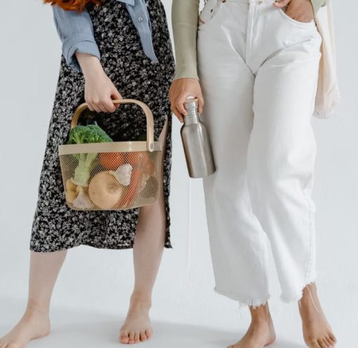 Two women holding reusable items, promoting sustainable living.