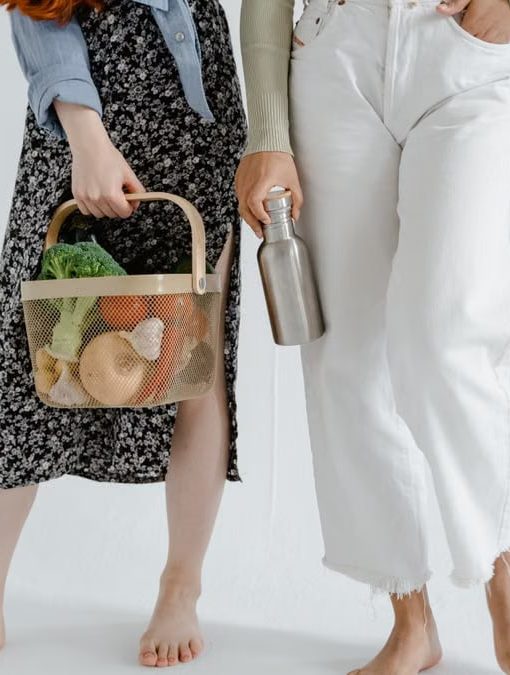 Two women holding reusable items, promoting sustainable living.