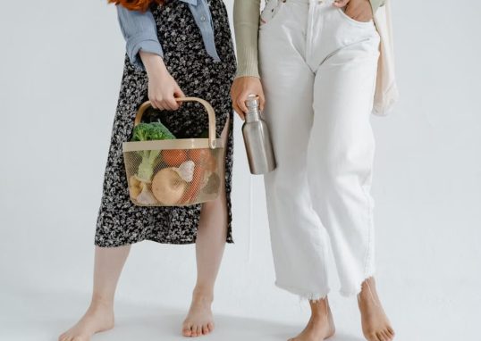 Two women holding reusable items, promoting sustainable living.