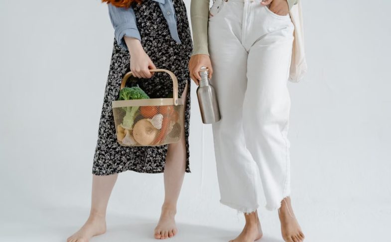 Two women holding reusable items, promoting sustainable living.
