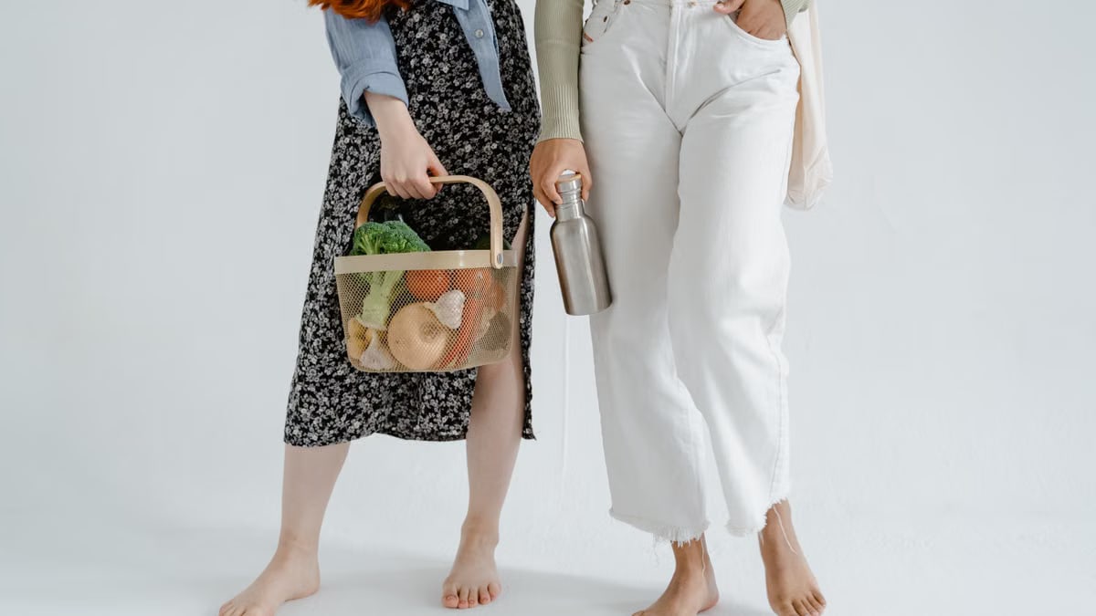 Two women holding reusable items, promoting sustainable living.