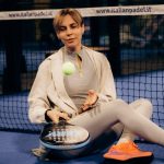 Female player sitting on indoor padel court with gear after match.