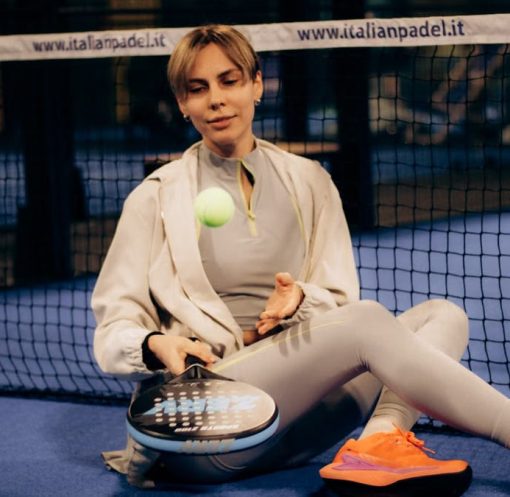 Female player sitting on indoor padel court with gear after match.